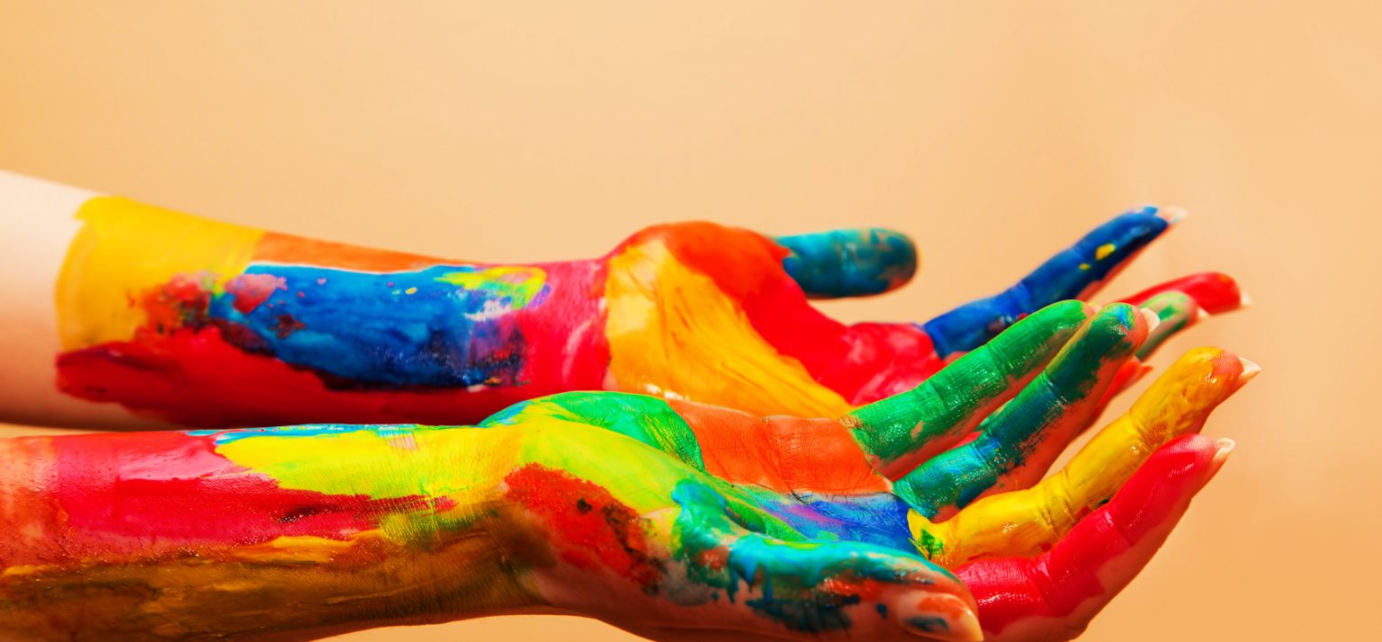 Painted hands, colorful fun. Creative, funny and artistic means happy! Orange background wall